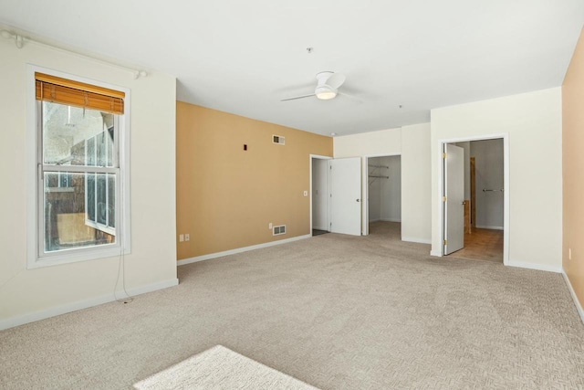 unfurnished bedroom with a spacious closet, light colored carpet, visible vents, and baseboards