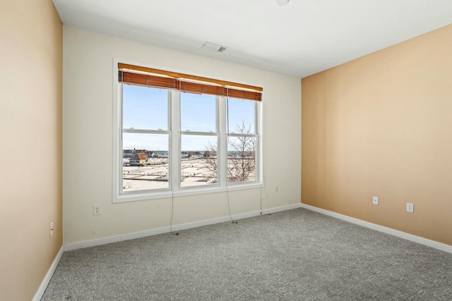 carpeted empty room featuring baseboards