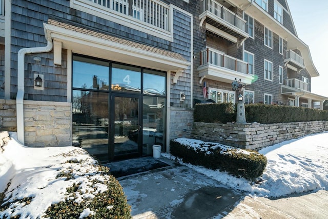 snow covered property entrance with stone siding