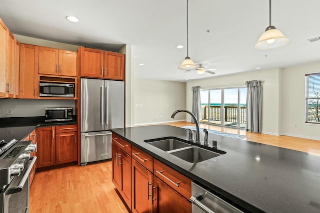 kitchen featuring dark countertops, premium appliances, a wealth of natural light, and a sink