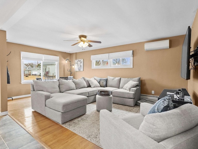 living area with a baseboard heating unit, light wood-style flooring, baseboards, and a wall mounted air conditioner