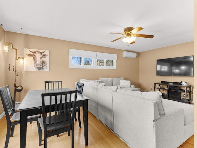 living area with light wood-style floors, an AC wall unit, and ceiling fan