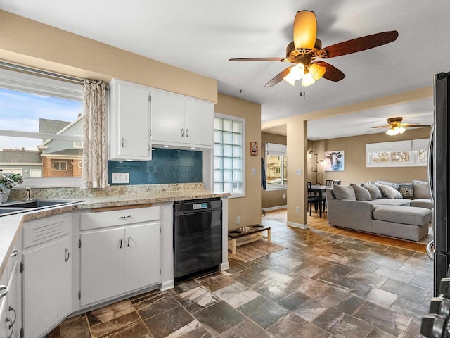 kitchen with backsplash, stone finish flooring, light countertops, white cabinetry, and a sink