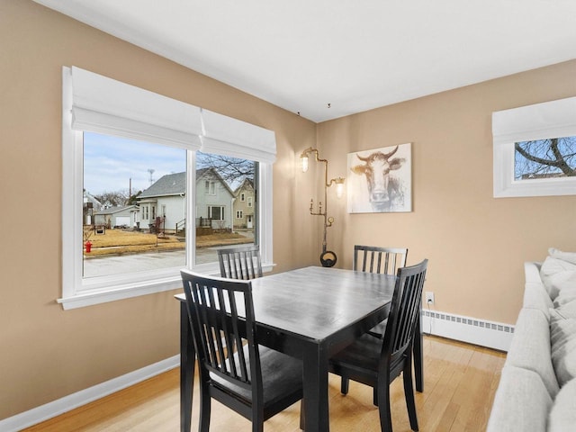 dining room with light wood-style floors, baseboards, and a baseboard radiator