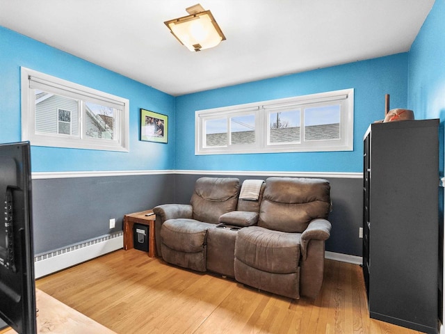 living room featuring a wealth of natural light, baseboard heating, baseboards, and wood finished floors