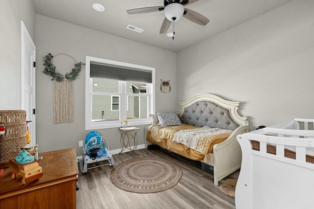 bedroom with visible vents, a ceiling fan, baseboards, and wood finished floors