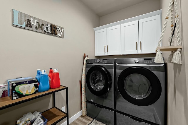 washroom featuring light wood-type flooring, cabinet space, baseboards, and washing machine and clothes dryer