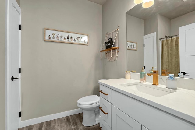 bathroom with a shower with curtain, toilet, wood finished floors, baseboards, and vanity