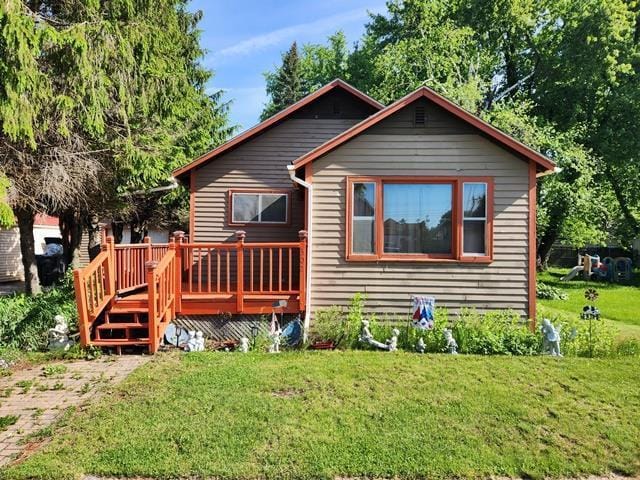 rear view of property featuring a wooden deck and a yard