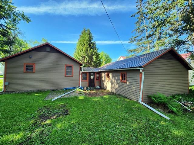 rear view of property featuring metal roof and a yard