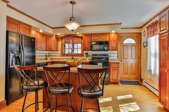 kitchen featuring light wood finished floors, ornamental molding, a sink, black appliances, and a baseboard heating unit