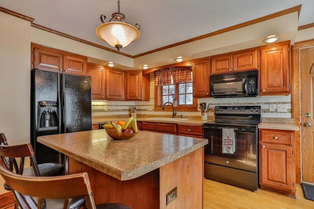 kitchen featuring a sink, black appliances, a kitchen bar, crown molding, and tasteful backsplash