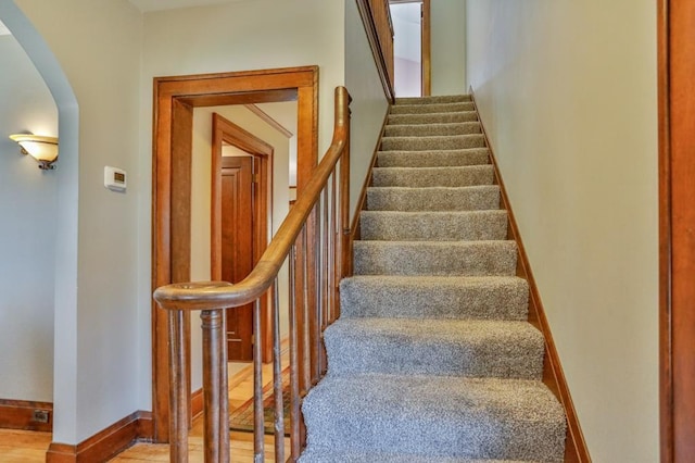 staircase with baseboards and arched walkways