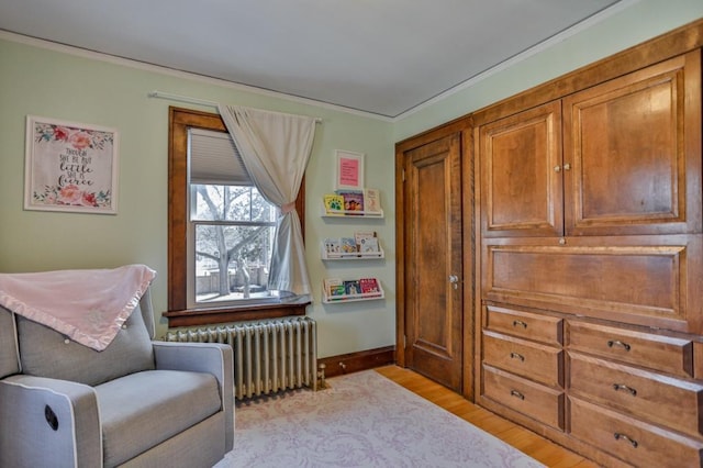 sitting room with baseboards, light wood-style flooring, and radiator heating unit