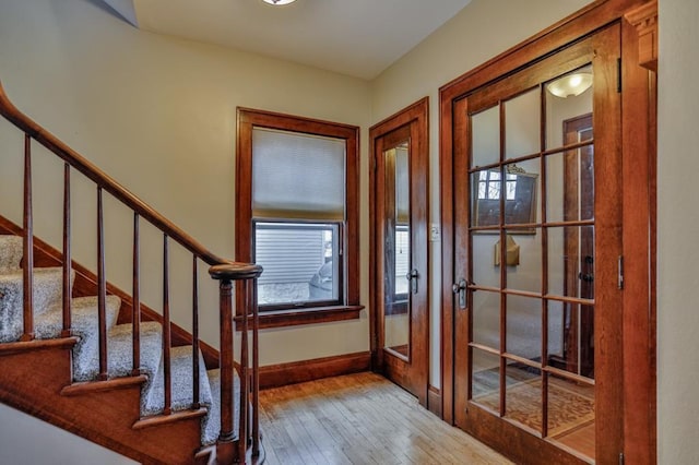 entryway with baseboards, wood-type flooring, and stairs