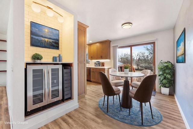 dining space featuring wine cooler, light wood-style flooring, and baseboards