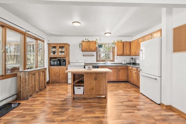 kitchen featuring baseboard heating, white appliances, a center island, and light wood-type flooring