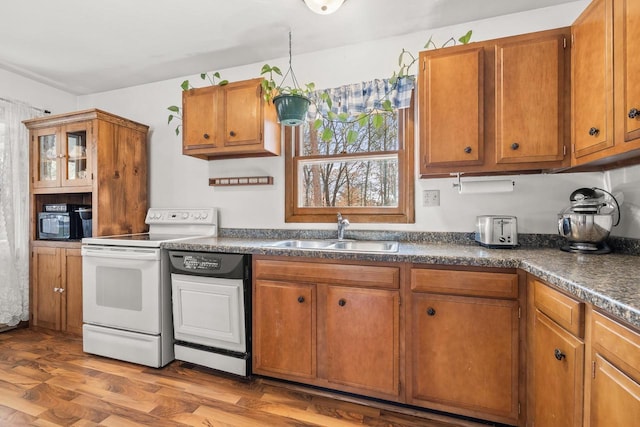 kitchen with dishwasher, dark countertops, white electric range, and a sink