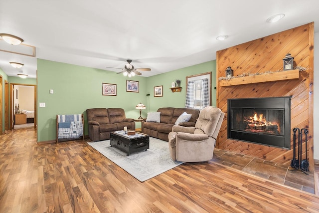 living area with a glass covered fireplace, wood finished floors, and baseboards