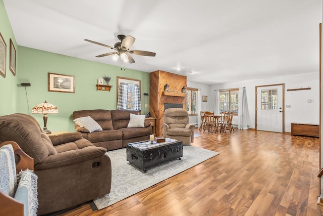 living area with a wealth of natural light, wood finished floors, and a ceiling fan