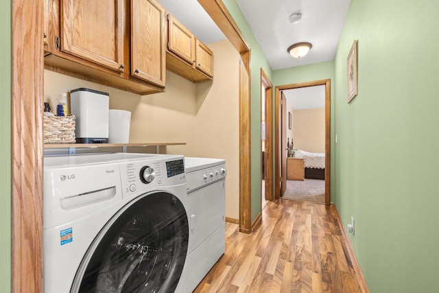 laundry room featuring light wood-type flooring, cabinet space, separate washer and dryer, and baseboards