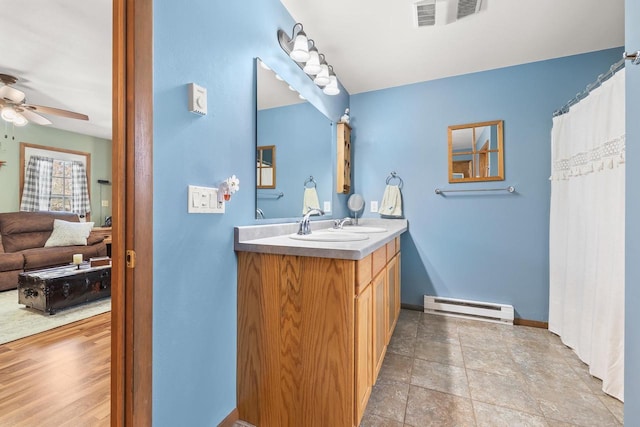 ensuite bathroom with visible vents, a baseboard heating unit, baseboards, ceiling fan, and vanity