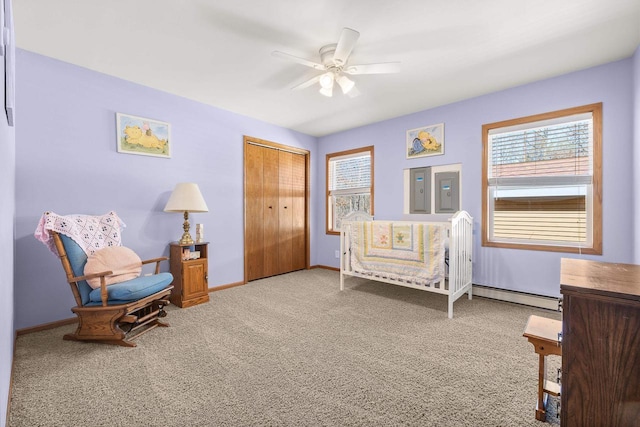 bedroom featuring a closet, multiple windows, baseboard heating, and carpet flooring