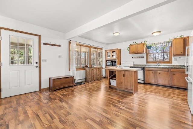 kitchen featuring beamed ceiling, brown cabinets, a healthy amount of sunlight, and wood finished floors