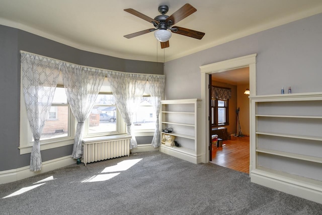 empty room with carpet flooring, radiator, and ceiling fan