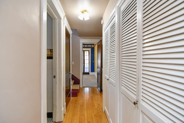 hall with baseboards and light wood finished floors