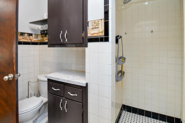 full bathroom with tiled shower, toilet, tile walls, and vanity