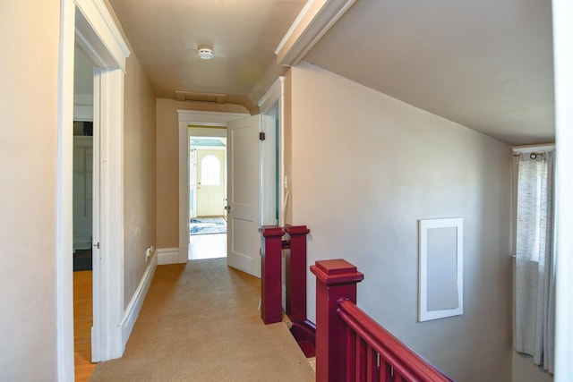 corridor featuring an upstairs landing, light colored carpet, and baseboards