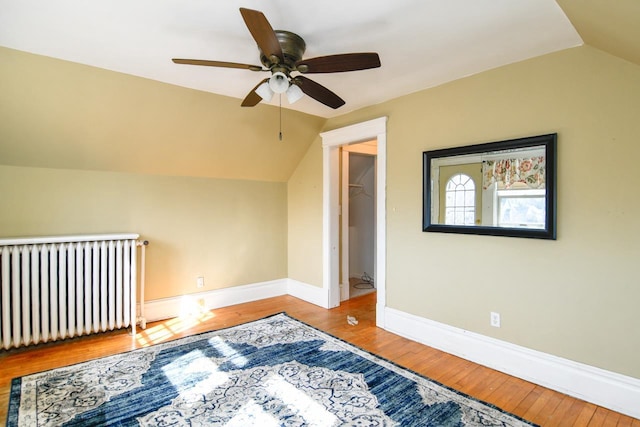 additional living space featuring radiator, baseboards, lofted ceiling, wood finished floors, and a ceiling fan