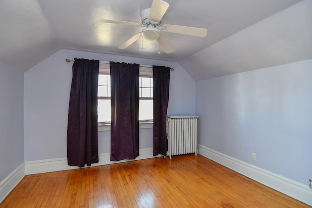 additional living space featuring radiator, baseboards, lofted ceiling, ceiling fan, and hardwood / wood-style flooring