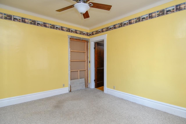 carpeted spare room featuring a ceiling fan and baseboards