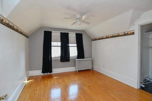 bonus room with radiator, a ceiling fan, baseboards, vaulted ceiling, and light wood-type flooring