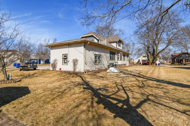 view of side of property featuring a lawn and a shingled roof