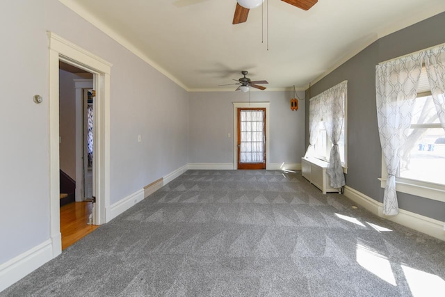 carpeted empty room with baseboards, ceiling fan, and crown molding