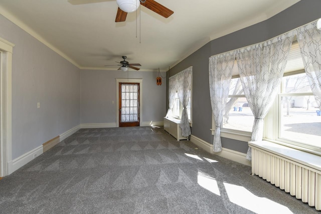 carpeted spare room with radiator, baseboards, ceiling fan, and ornamental molding