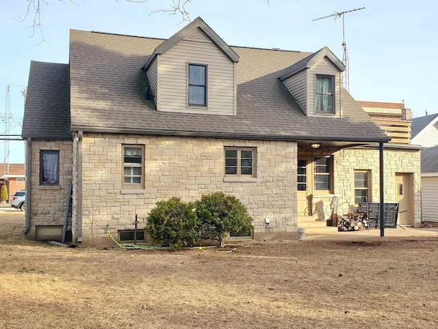 rear view of property with roof with shingles and a patio area