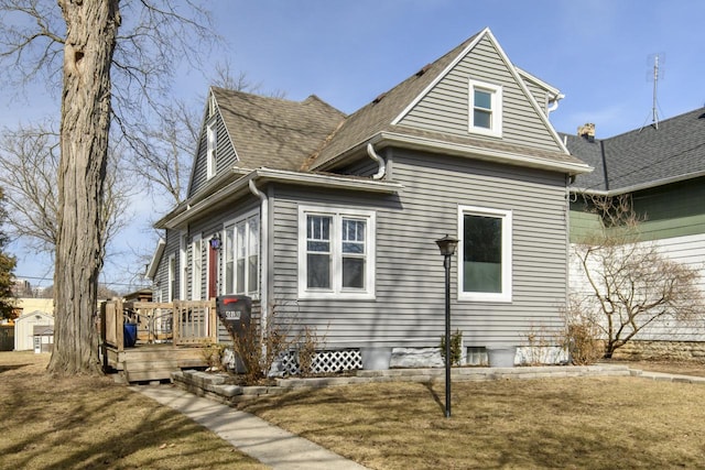 view of side of home with roof with shingles and a deck