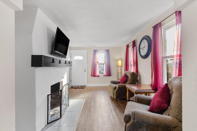 living area with baseboards, light wood-style flooring, and a fireplace