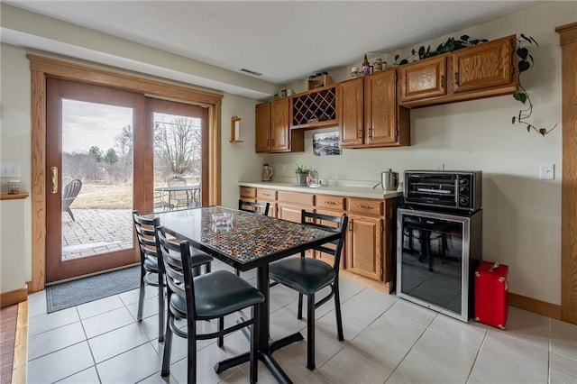 kitchen featuring brown cabinetry, beverage cooler, a toaster, a sink, and light countertops