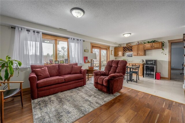 living room with light wood-style flooring, beverage cooler, and a textured ceiling