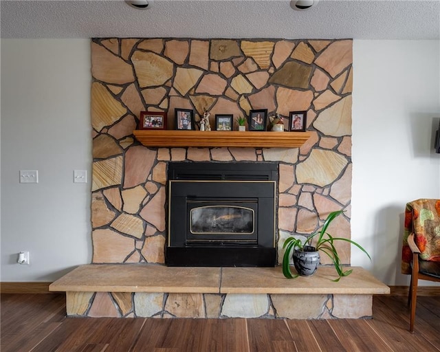 room details with a fireplace, a textured ceiling, baseboards, and wood finished floors