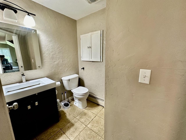 bathroom with toilet, baseboard heating, a textured wall, tile patterned floors, and vanity