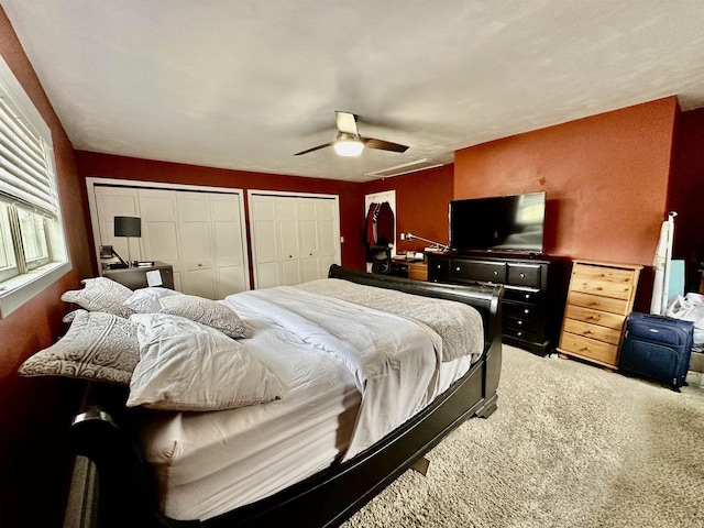 bedroom with two closets, carpet, and ceiling fan