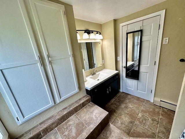 bathroom featuring a baseboard radiator, vanity, and a textured wall