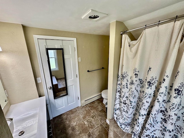 bathroom with toilet, a shower with shower curtain, a baseboard radiator, baseboards, and a textured wall