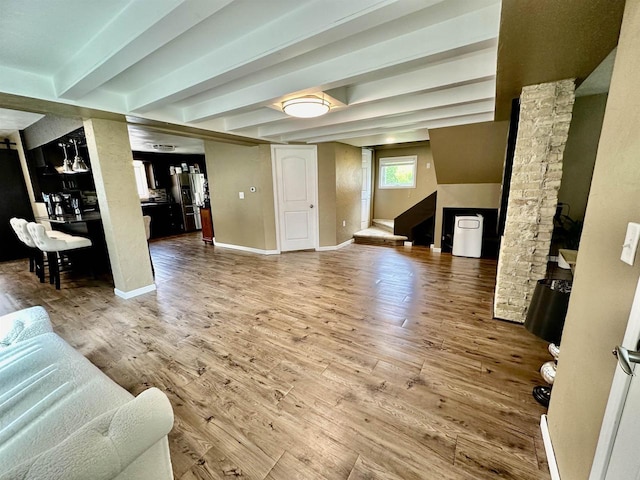 living room featuring baseboards, beam ceiling, and wood finished floors